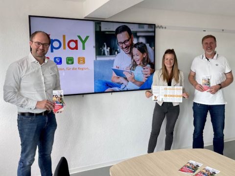 3 Personen stehen vor Bildschirm mit Yplay Logo, Glasfaserausbau Echzell