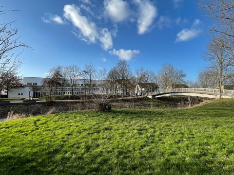 Großes Gebäude hinter Bäumen und Wiese, Karben