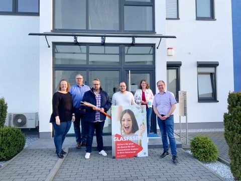Sechs Personen aus Ortenberg und von Yplay, die ein Plakat und ein Glasfaser-Leerrohr in der Hand halten