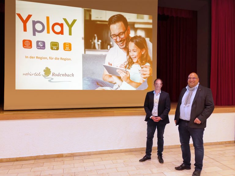 Peer Kohlstetter mit anderer Person steht vor einer Bühne mit Leinwand die Yplay Logo für Rodenbach zeigt