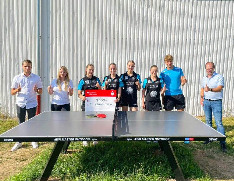 Gruppe Personen steht vor einer Tischtennisplatte, 2 davon halten Spendenquittung von der Firma Yplay für den TTC Salmünster aus Bad Soden-Salmünster