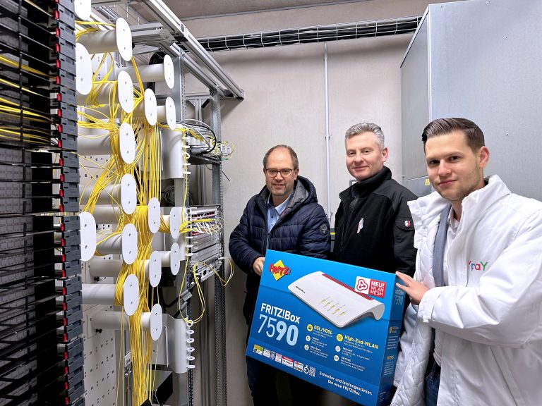 3 Personen stehen im POP, Hauptverteiler und halten große Fritz Box Schachtel zur Glasfaser Aktivierung in Ronneburg