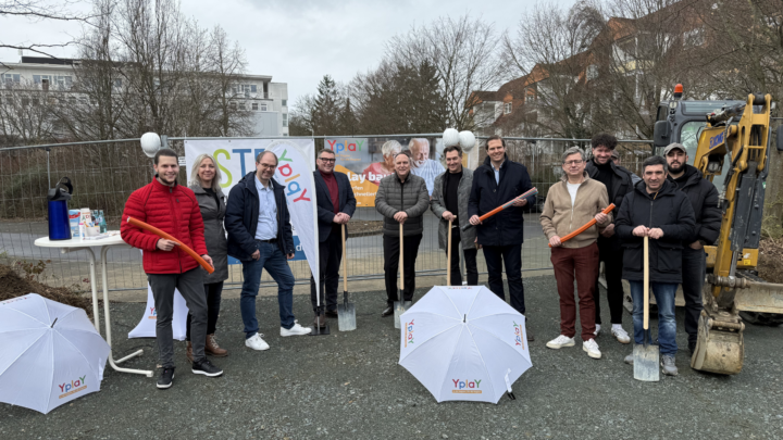 Spatenstich für den Glasfaserausbau in Bad Nauheim: Vertreter von Yplay Germany, der Stadt Bad Nauheim, Primevest Capital und STEL stehen gemeinsam mit Bürgermeister Klaus Kreß vor einem Bagger und halten symbolisch Spaten sowie Glasfaserrohre für den Start des Ausbauprojekts.