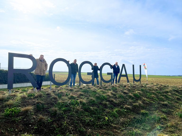 Personen an großen Buchstaben "Roggau" auf einer Wiese neben Yplay Schild