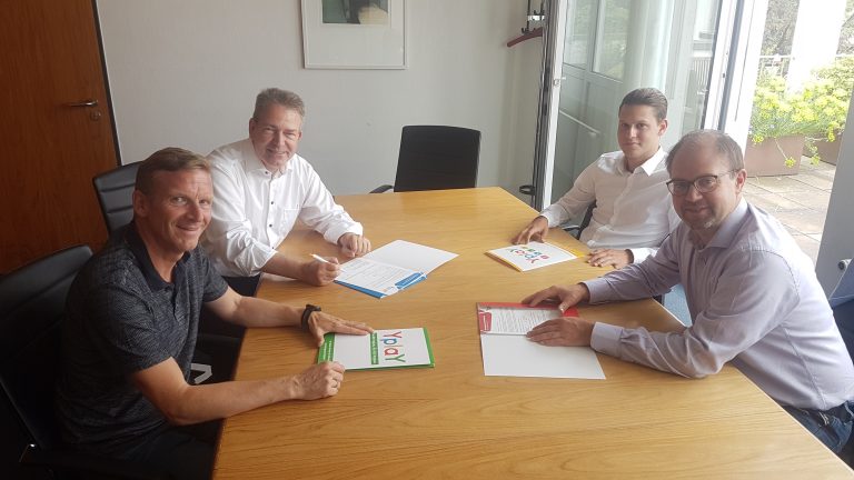Vier Männer sitzen an Konferenztisch mit Yplay-Bestellmappen wegen des Glasfaserausbaus der Stadt Karben