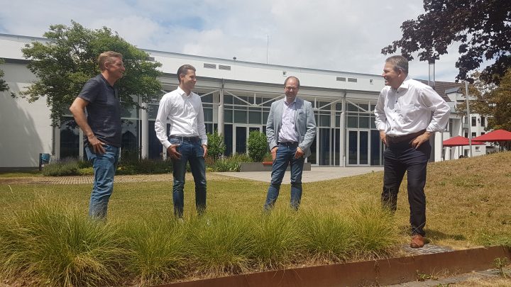 4 Männer stehen auf einer Wiese vor einem Gebäude wegen des Glasfaserausbaus Karben